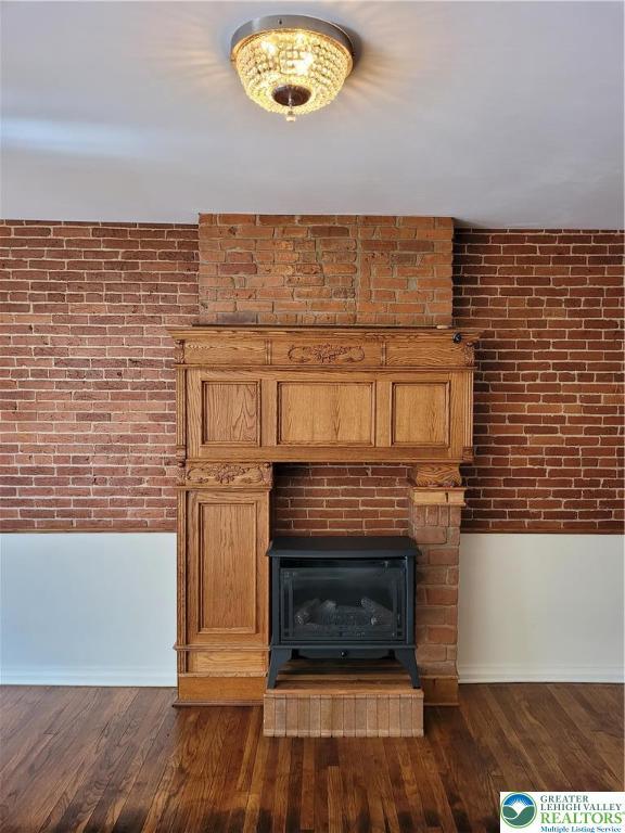 detailed view of baseboards, wood finished floors, and a fireplace