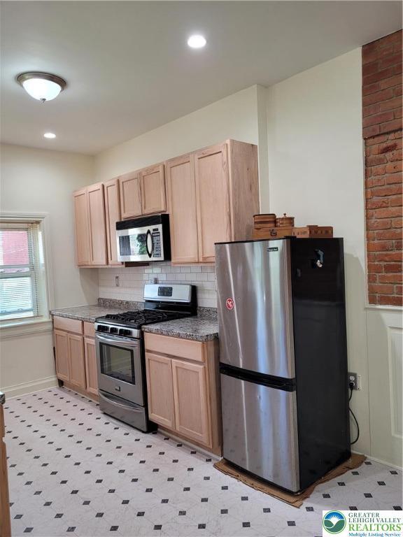 kitchen with stainless steel appliances, light brown cabinetry, backsplash, dark countertops, and recessed lighting