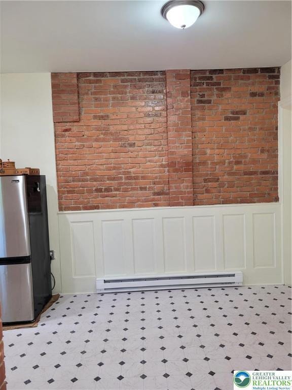 kitchen view of freestanding refrigerator, a wainscoted wall, brick wall, a decorative wall, and a baseboard heating unit