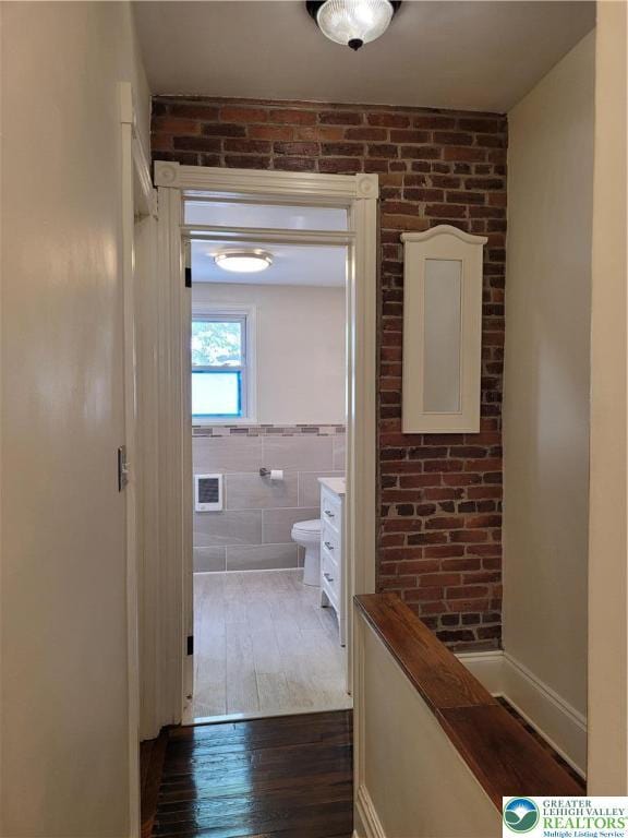 corridor featuring wood-type flooring and tile walls