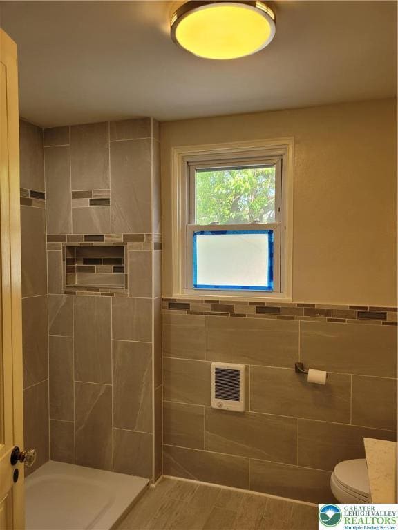 full bathroom with a shower, toilet, tile walls, a wainscoted wall, and a bathtub