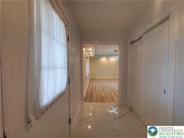 corridor with baseboards and marble finish flooring