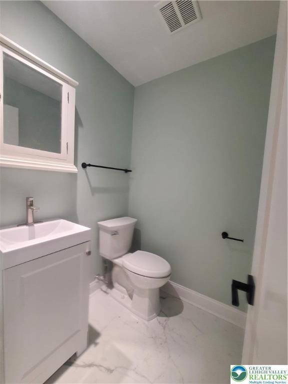 half bath with marble look tile flooring, vanity, toilet, and baseboards