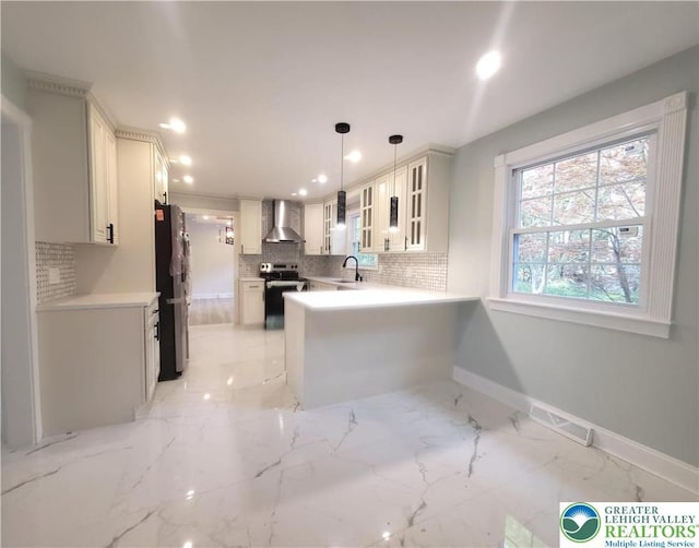 kitchen with wall chimney range hood, freestanding refrigerator, stainless steel electric range oven, backsplash, and glass insert cabinets