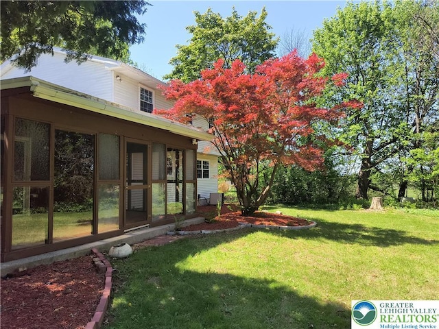 view of green lawn with a sunroom