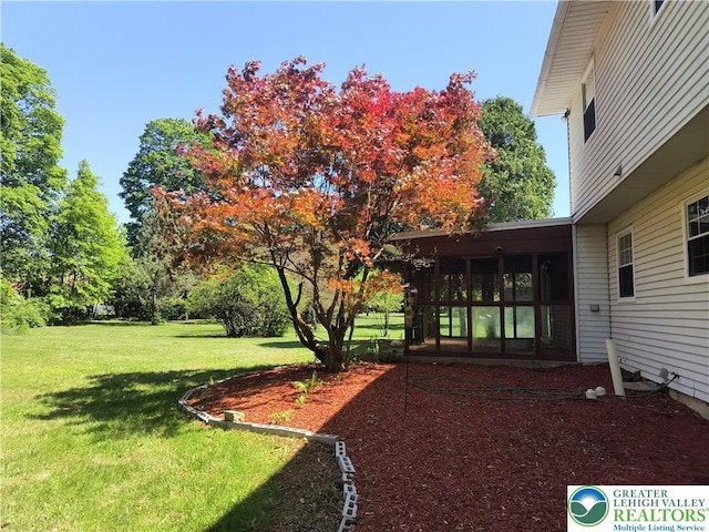 view of grassy yard with a sunroom