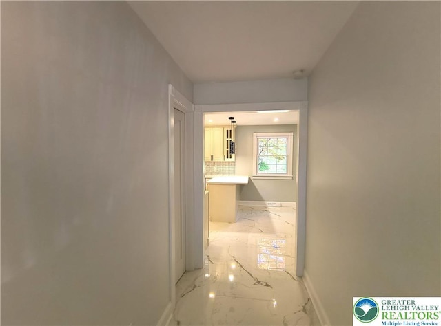 corridor with light marble finish flooring and baseboards