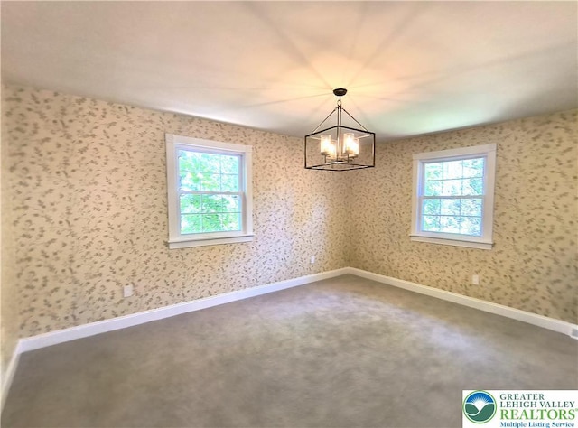 unfurnished dining area with plenty of natural light, a chandelier, carpet floors, and baseboards