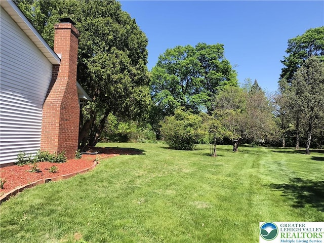 view of green lawn featuring view of scattered trees