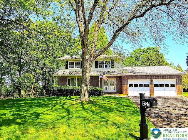 traditional home with an attached garage, a front yard, brick siding, and driveway