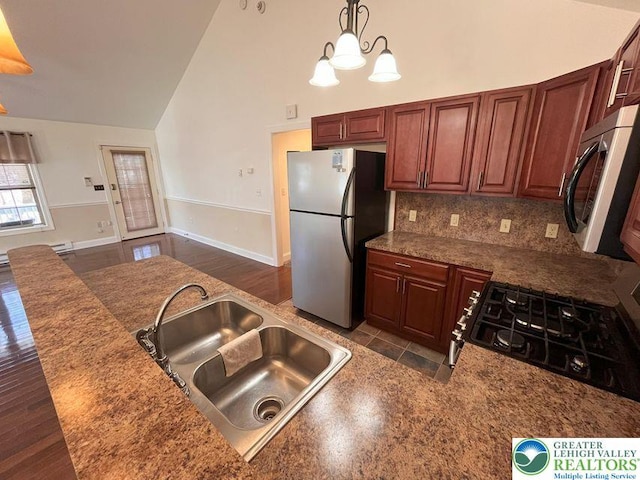kitchen with stainless steel appliances, a sink, high vaulted ceiling, decorative backsplash, and hanging light fixtures