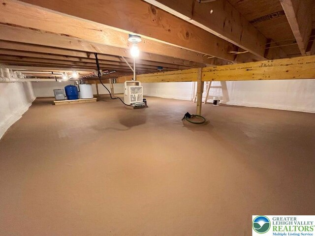 unfinished basement with water heater and a water pressure tank