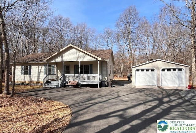ranch-style home featuring a porch, a detached garage, and an outbuilding