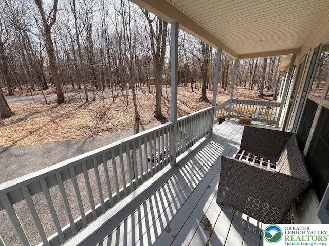 deck featuring covered porch and view of wooded area