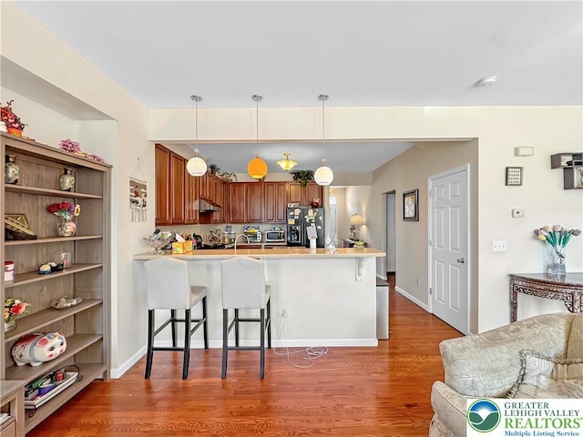 4527 Bellflower Way, Upper Macungie Twp, PA 18104 - kitchen with refrigerator with ice dispenser, a peninsula, a kitchen breakfast bar, light wood finished floors, and under cabinet range hood