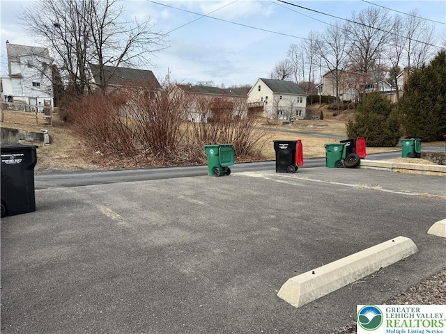 view of asphalt street featuring a residential view and curbs