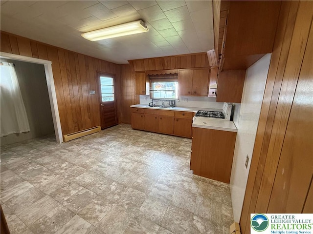 kitchen with baseboard heating, light countertops, brown cabinets, wood walls, and white appliances