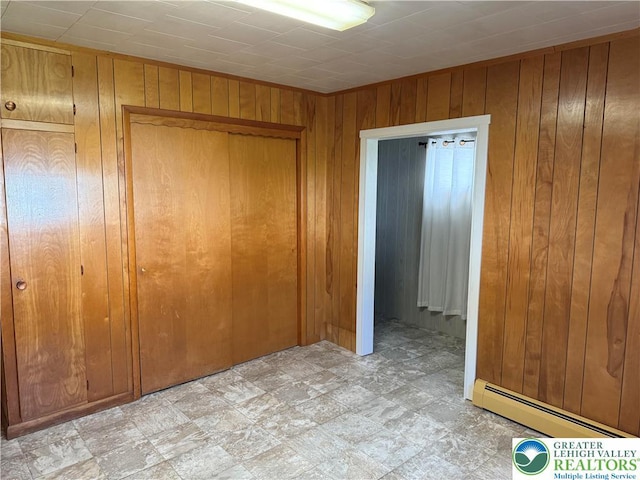 unfurnished bedroom featuring baseboard heating and wooden walls