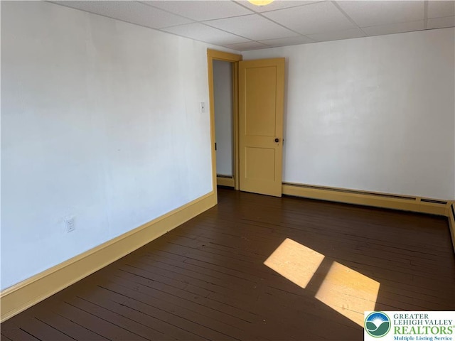 unfurnished room featuring wood-type flooring, baseboards, a paneled ceiling, and a baseboard heating unit