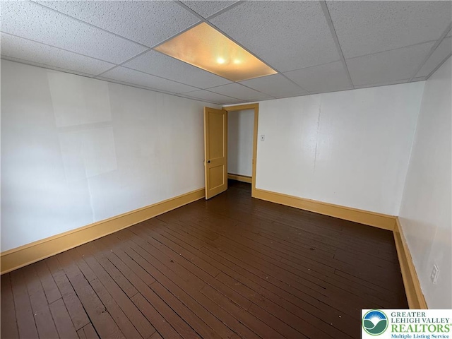 unfurnished room with baseboards, dark wood-style floors, and a drop ceiling