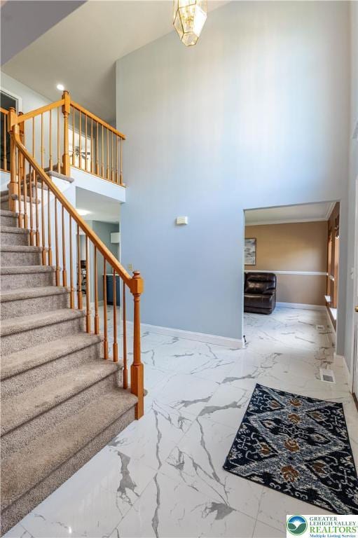 stairs featuring marble finish floors, baseboards, and a high ceiling