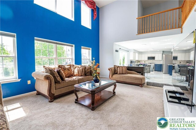living area with a high ceiling and light colored carpet