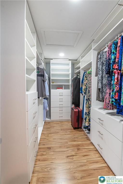 walk in closet with attic access and light wood-style flooring