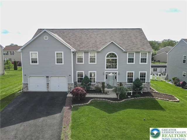view of front of property with an attached garage, asphalt driveway, stone siding, a front yard, and a shingled roof
