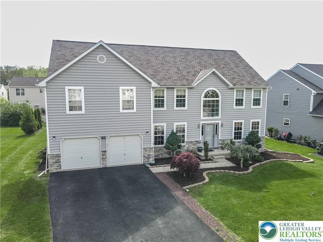 colonial house featuring stone siding, a front lawn, asphalt driveway, and a garage