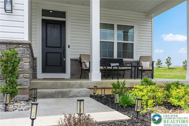 entrance to property featuring a porch and stone siding