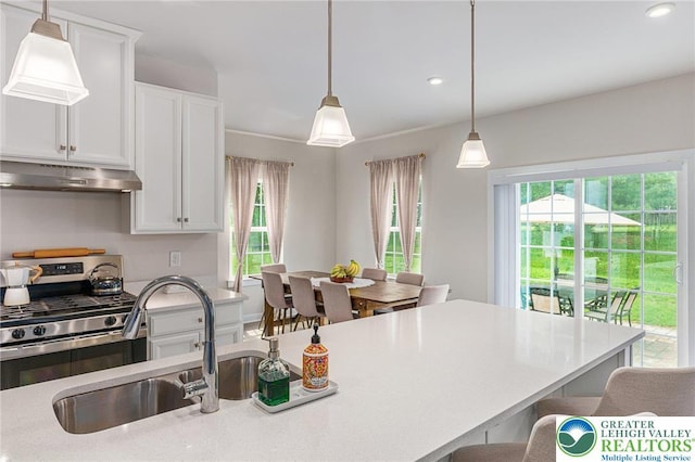 kitchen featuring under cabinet range hood, stainless steel gas stove, healthy amount of natural light, a sink, and recessed lighting