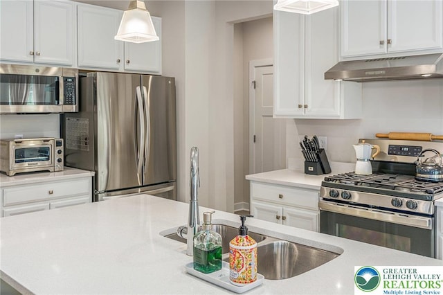 kitchen with stainless steel appliances, under cabinet range hood, white cabinets, light countertops, and a sink