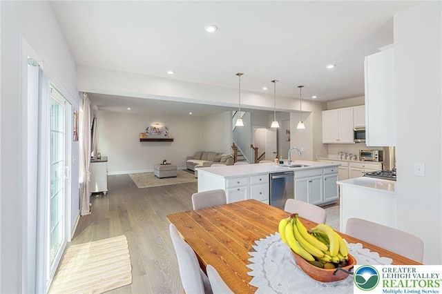 kitchen with stainless steel appliances, a sink, an island with sink, open floor plan, and light countertops