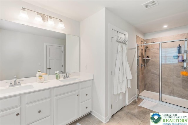 bathroom featuring a shower stall, double vanity, baseboards, tile patterned flooring, and a closet