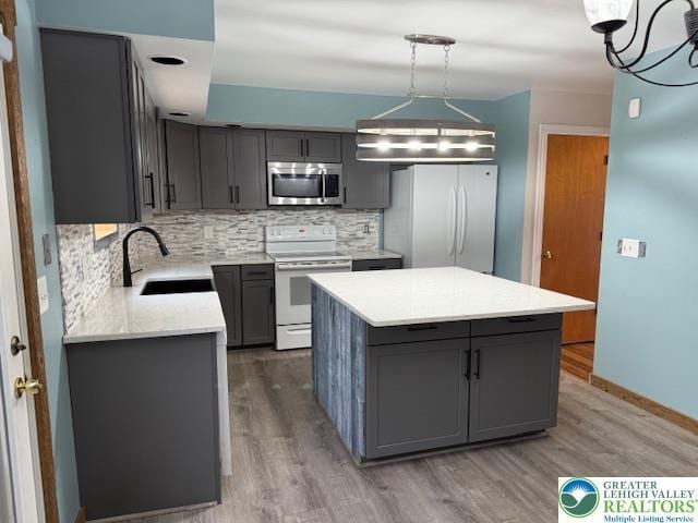 kitchen featuring white appliances, a sink, gray cabinetry, tasteful backsplash, and light countertops
