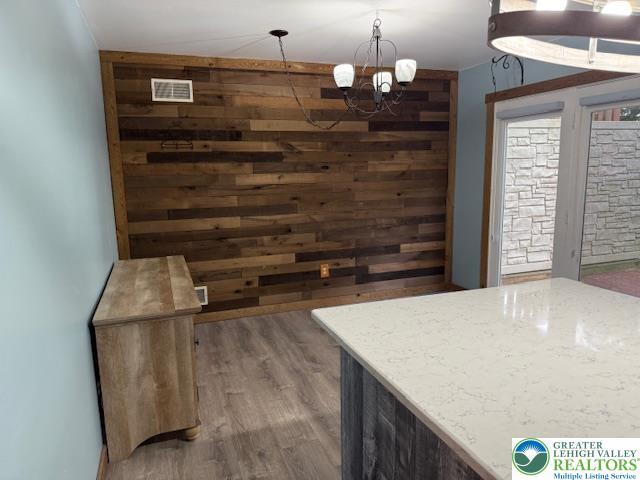 dining room featuring wood finished floors, a chandelier, and wood walls