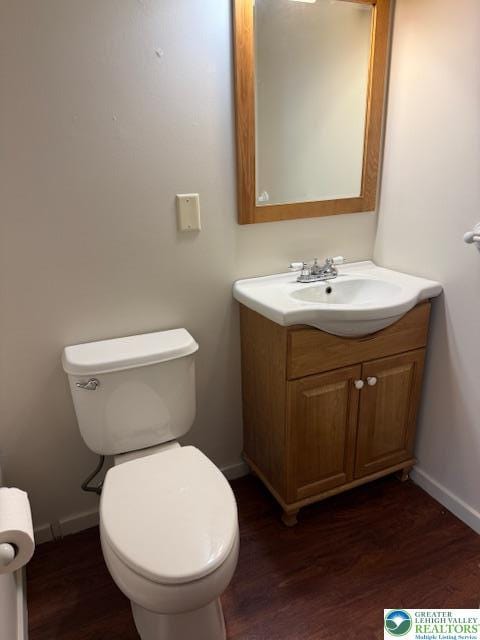 bathroom featuring wood finished floors, baseboards, toilet, and vanity
