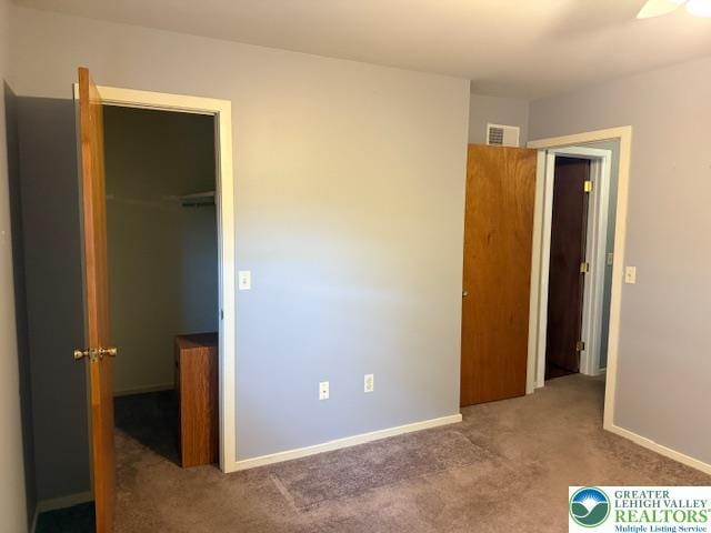 unfurnished bedroom with carpet flooring, a spacious closet, a closet, and baseboards