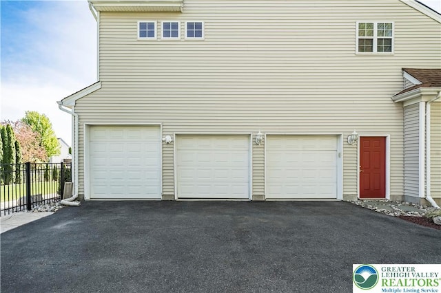 garage with asphalt driveway and fence