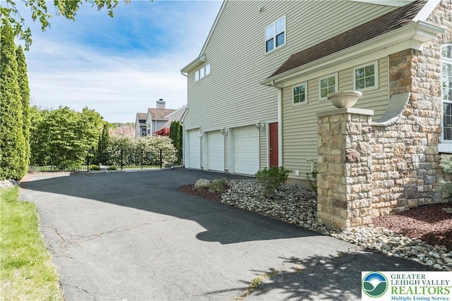 view of property exterior featuring driveway, a garage, and stone siding