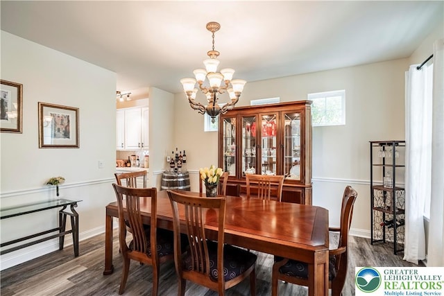 dining area featuring a chandelier, wood finished floors, and baseboards