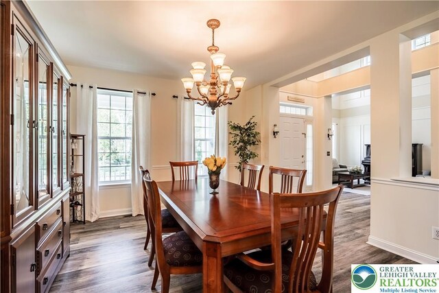 dining area featuring a chandelier, dark wood-style flooring, and baseboards