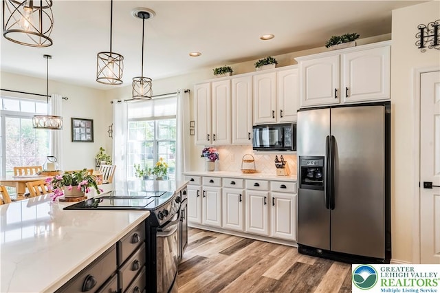 kitchen with black appliances, white cabinets, light wood-style floors, hanging light fixtures, and a chandelier