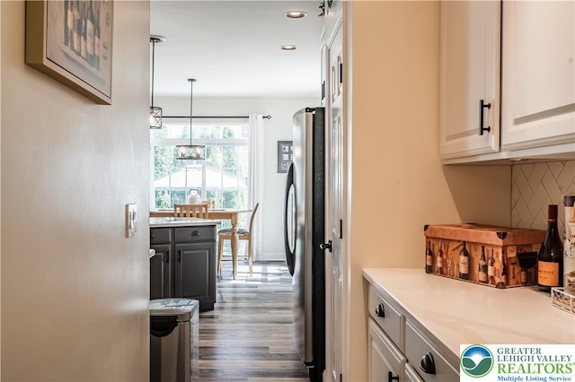 kitchen with a chandelier, decorative backsplash, freestanding refrigerator, wood finished floors, and light countertops