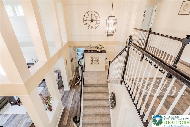 stairs with a chandelier and wood finished floors