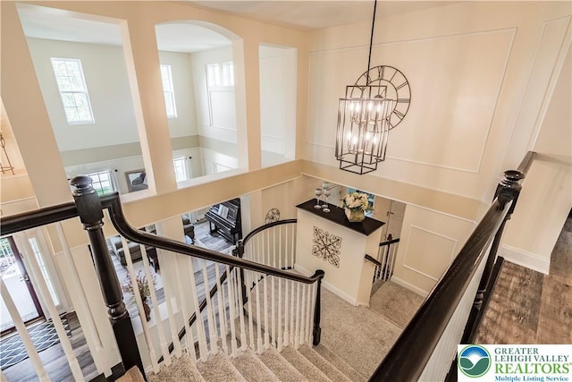 staircase featuring a chandelier and arched walkways
