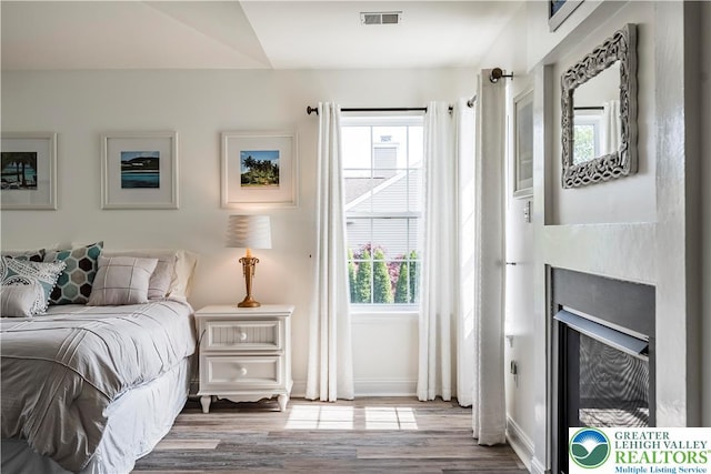 bedroom with wood finished floors, a fireplace, and baseboards