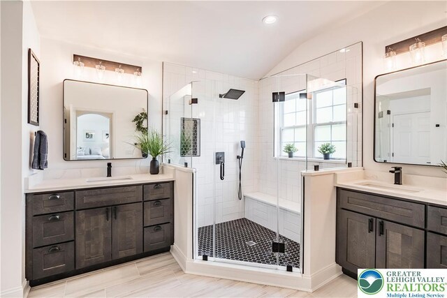 bathroom featuring a shower stall, lofted ceiling, two vanities, and recessed lighting