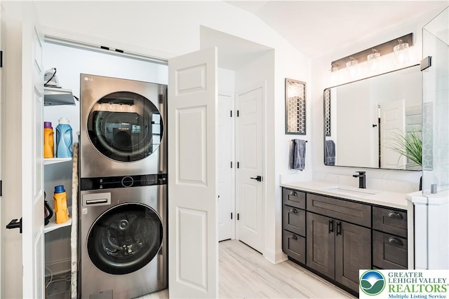 laundry room featuring stacked washer / drying machine and light wood-style flooring