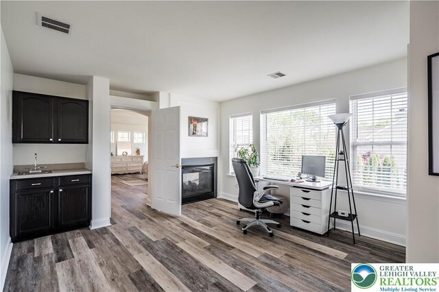 office featuring a multi sided fireplace, wood finished floors, and healthy amount of natural light